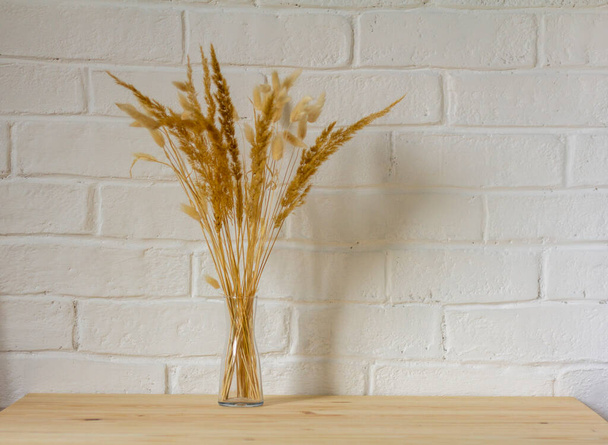 Осінній букет із сушених трав у прозорій вазі на дерев'яному столі з копією простору
 - Фото, зображення