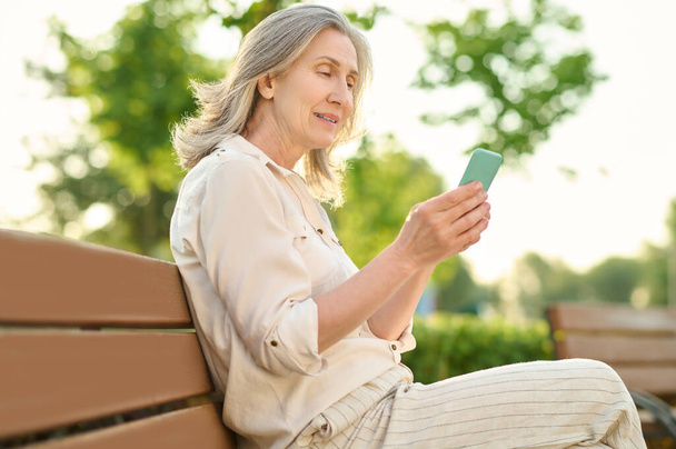 Serious woman with smartphone on bench - Foto, Bild