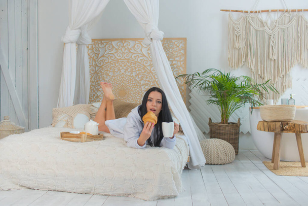 jeune femme prenant le petit déjeuner au lit dans une chambre lumineuse - Photo, image