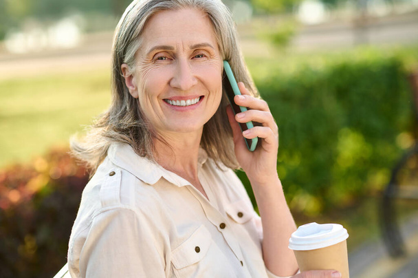 Affable smiling woman communicating by smartphone - Фото, зображення