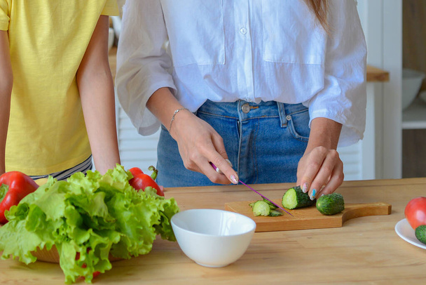 mamá enseña a su hijita a cocinar alimentos saludables en la cocina - Foto, Imagen