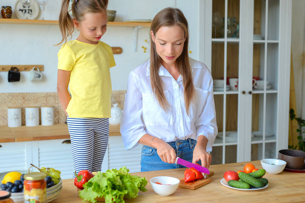 Máma učí malou dceru vařit zdravé jídlo v kuchyni - Fotografie, Obrázek
