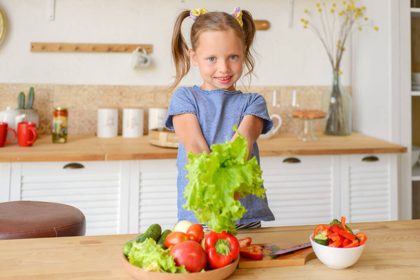 klein meisje met groenten en fruit in de keuken - Foto, afbeelding
