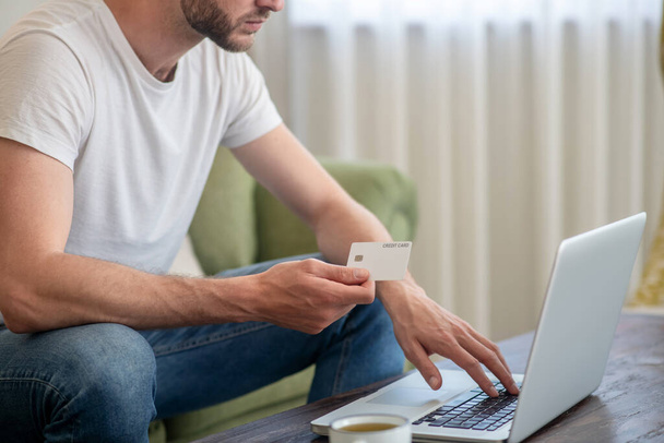 A man sitting at the laptop and paying by credit card online - Foto, Imagem