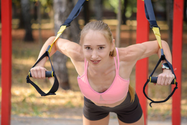 Donna che fa push-up braccia di formazione con cinghie di fitness trx in palestra sport sano concetto di allenamento stile di vita - Foto, immagini
