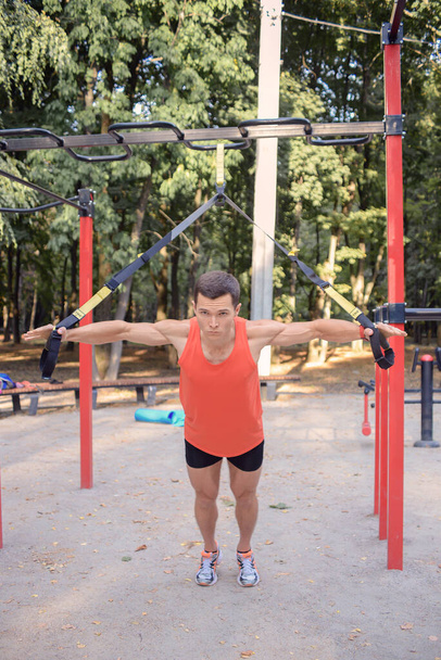 sports guy is exercising in the park on the playground in summer - Photo, Image