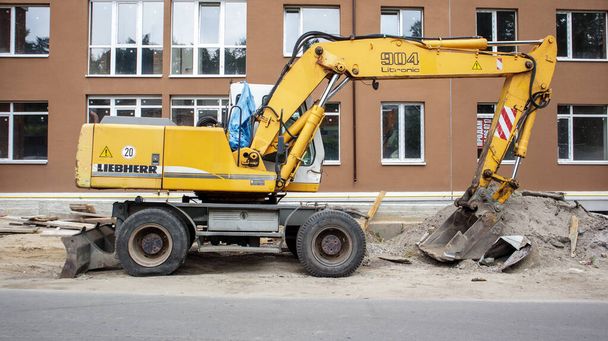 Ruchomy dźwig o żółtym kolorze na tle budowanego budynku. Międzynarodowy producent sprzętu. Koparka służy do robót ziemnych. Ukraina, Kijów - 11 września 2021 - Zdjęcie, obraz