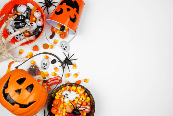 Halloween Trick oder Leckerbissen Seitenrand mit Jack o Laterne Eimer und verschiedene Süßigkeiten. Overhead-Ansicht auf weißem Hintergrund mit Kopierraum. - Foto, Bild