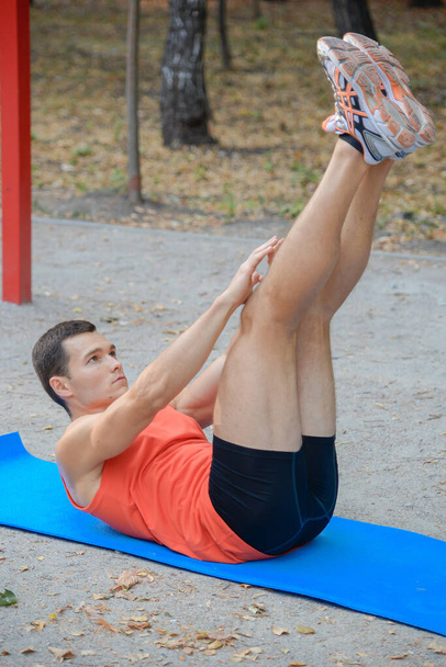 sports guy is exercising in the park on the playground in summer - Photo, Image