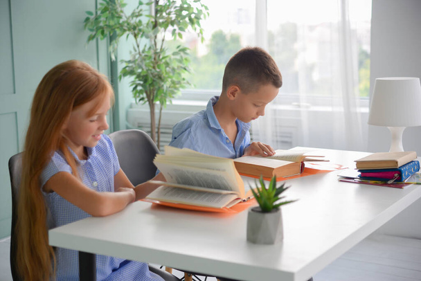 Takaisin kouluun. Onnellinen hymyilevä tyttö ja poika lukeminen ja kirjoittaminen pöydässä. luokkahuoneessa olevat lapset tekevät läksyjä - Valokuva, kuva