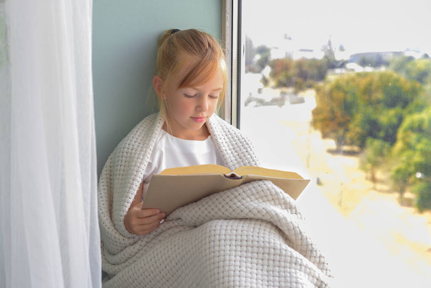 słodkie dziewczyna uczennica czytanie książki przez okno w domu - Zdjęcie, obraz