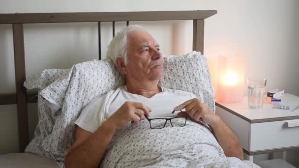 Yaşlanan yaşlı erkek, evde yatağında yorgunluktan ölüyor yalnız başına dinleniyor, virüsü tedavi ediyor mutsuz, termometreyi tutuyor. - Video, Çekim