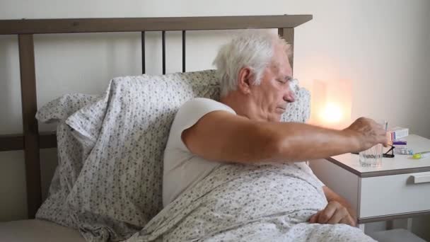 ouder worden oudere man man in bed thuis flat, moe ziek ziek alleen gepensioneerd en rusten virus verzorgen ongelukkig verdrietig, water drinken, pick-up glas - Video