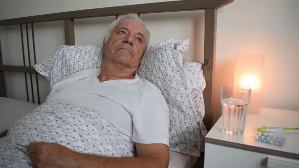 alternder älterer älterer Mann im Bett zu Hause Wohnung, müde Kranke krank allein Rentner und Ruhe Virus Pflege unglücklich traurig - Filmmaterial, Video