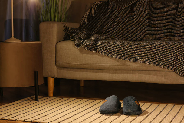 Mężczyzna miękkie kapcie na dywanie w pobliżu kanapy w domu - Zdjęcie, obraz