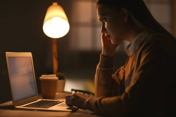 Junge Frau arbeitet abends am Laptop - Foto, Bild