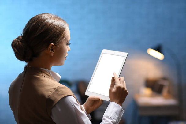 Νεαρή γυναίκα με υπολογιστή tablet που εργάζεται στο γραφείο τη νύχτα - Φωτογραφία, εικόνα