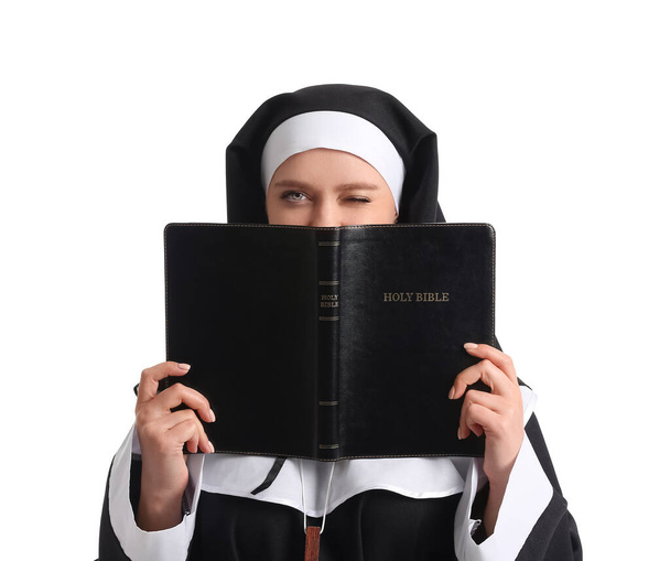 Νεαρή καλόγρια με Αγία Γραφή σε λευκό φόντο - Φωτογραφία, εικόνα