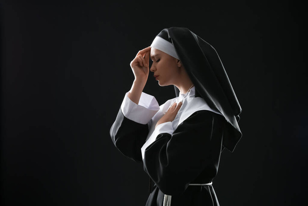 Fiatal imádkozó apáca sötét háttér - Fotó, kép