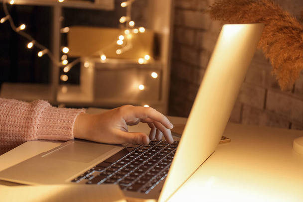 Жінка працює з ноутбуком за столом пізно ввечері, крупним планом
 - Фото, зображення