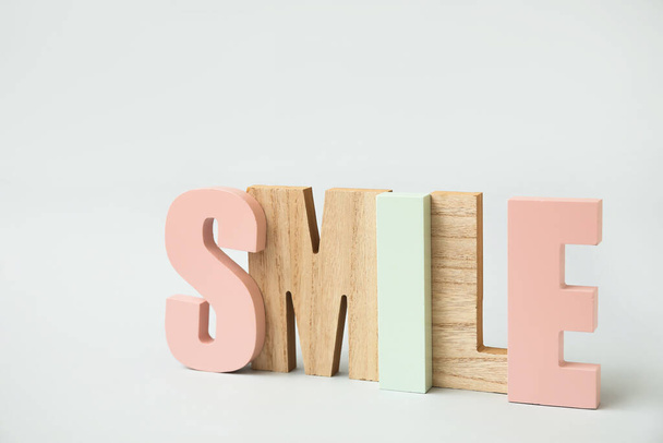 Stijlvol decor in de vorm van woord SMILE op lichte achtergrond - Foto, afbeelding