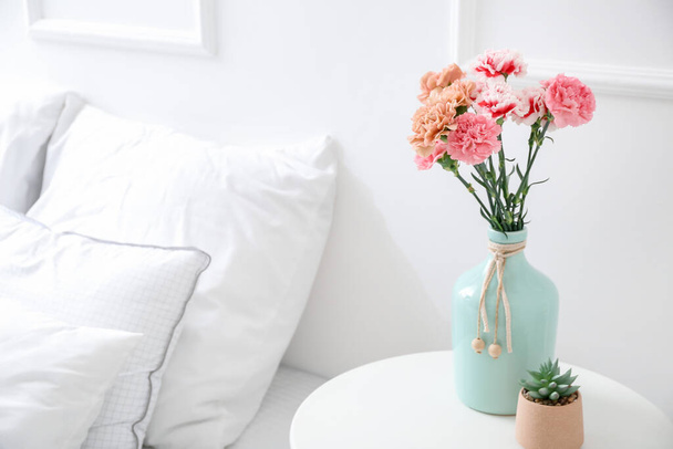 Vase with beautiful carnations on table in bedroom - Fotó, kép