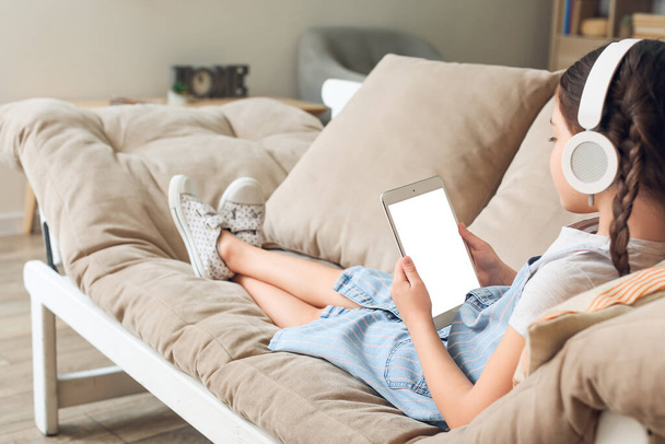 Kleines Mädchen mit Tablet-Computer hört zu Hause Hörbuch - Foto, Bild