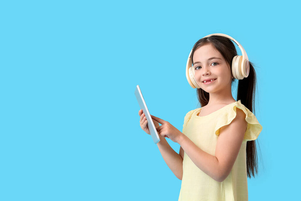 Kleines Mädchen mit Tablet-Computer und Kopfhörer auf farbigem Hintergrund - Foto, Bild