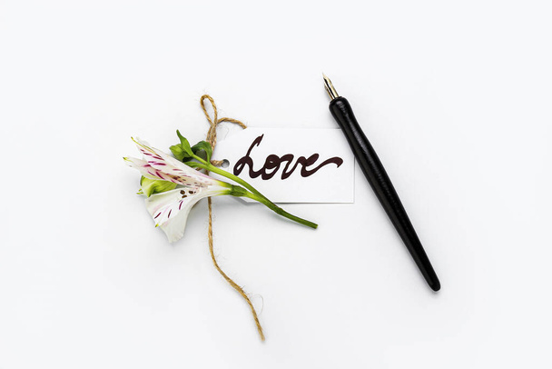 Paper with word LOVE, nib pen and flower on white background - Photo, Image
