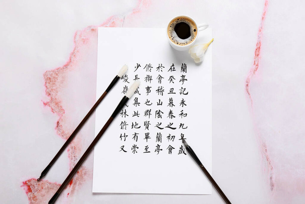 Бумага с иероглифами, кисточками и чашкой кофе на фоне гранжа - Фото, изображение