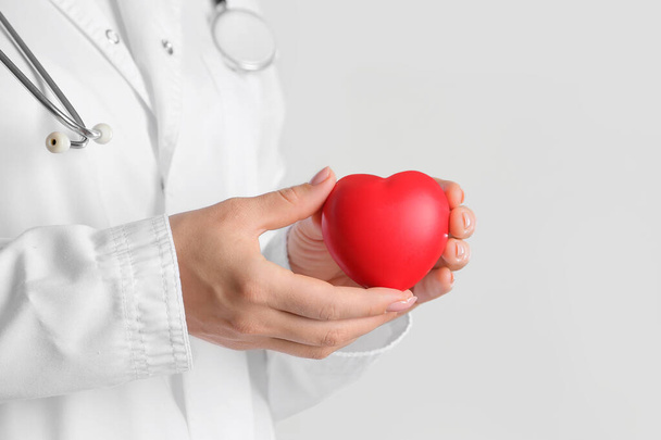Женщина-кардиолог с сердцем на светлом фоне, крупным планом - Фото, изображение