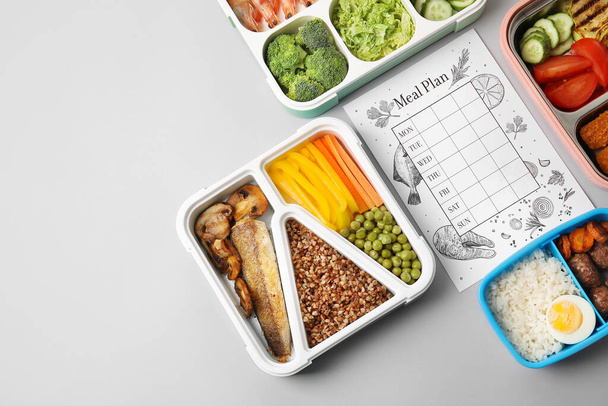 Containers met gezonde voeding en maaltijd plan op grijze achtergrond, close-up - Foto, afbeelding
