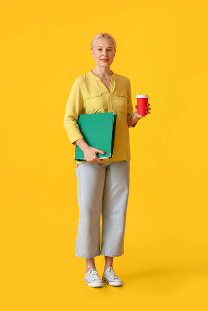 Porträt einer reifen Frau mit Ordner und Kaffee auf farbigem Hintergrund - Foto, Bild