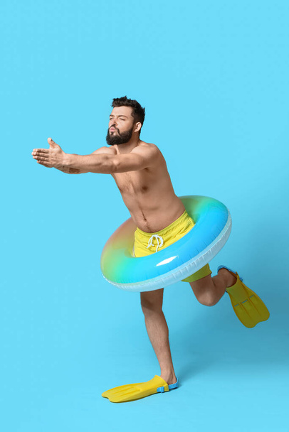Young man with inflatable ring and paddles on color background - Foto, imagen