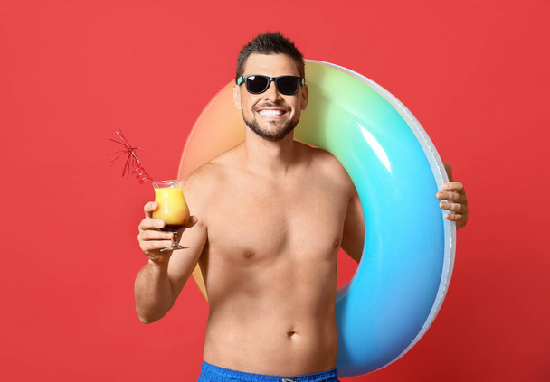 Young man with inflatable ring and cocktail on color background - Fotografie, Obrázek