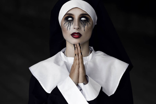 Woman dressed for Halloween as nun on dark background - Фото, изображение