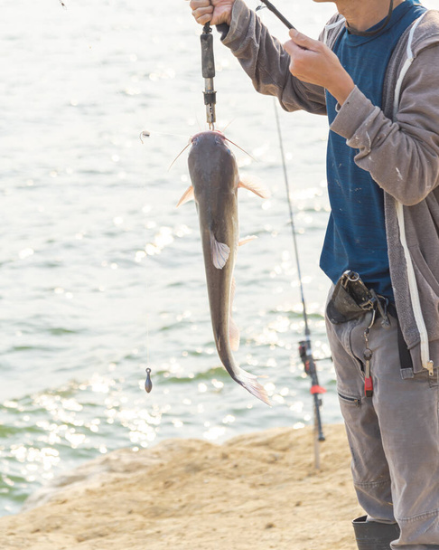 Pêcheur asiatique portant des bottes de pêche avec pince à lèvres canne et poisson gérer le poisson-chat près de Lavon Lake, Texas, Amérique. - Photo, image
