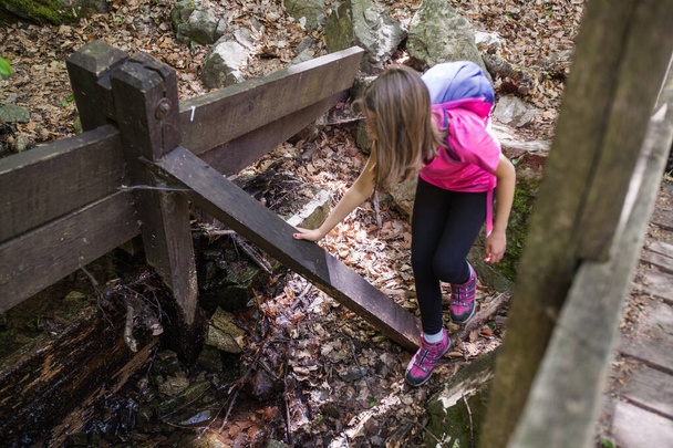 Little girl hiker refresh by water from forest creek. - Foto, afbeelding