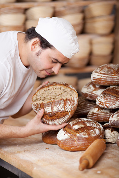 Male worker smelling bread - Foto, afbeelding