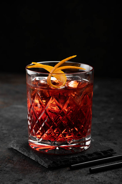 Cocktail classico vecchio stile in vetro retrò con ghiaccio e buccia d'arancia su sfondo nero - Foto, immagini