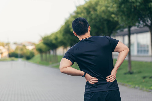 Asian man holding back pain after running and fitness - Фото, зображення