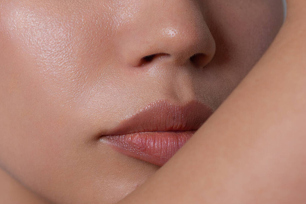 Close-up portrait of beautiful woman's purity face with nude lips make-up. Cute model with clean shiny skin and long neck. The place for your text, a gray background. Gives a kiss - Φωτογραφία, εικόνα
