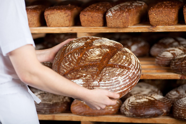 Female worker with round bread - Zdjęcie, obraz