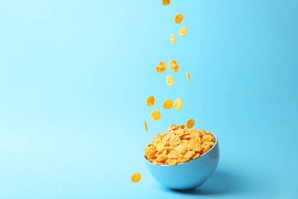 Delicious cornflakes falling into a plate on a colored background. - Fotografie, Obrázek