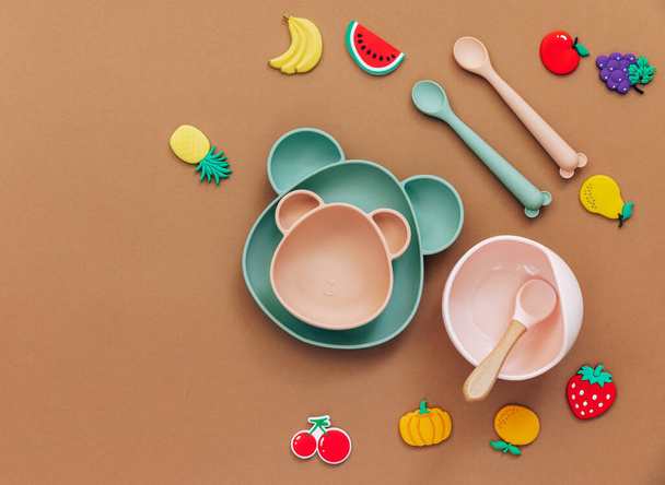 Flat lay composition with baby food accessory, plastic fruits, on light background. First baby food concept - Foto, Imagem