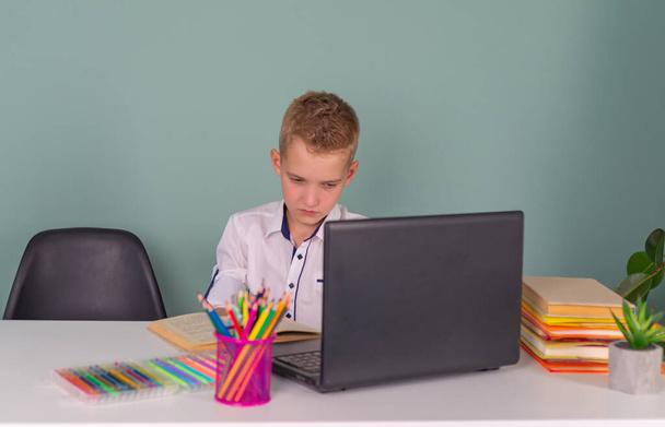 Zurück in die Schule! Ein nettes fleißiges Kind sitzt in der Schule am Laptop. Junge lernt im Unterricht - Foto, Bild