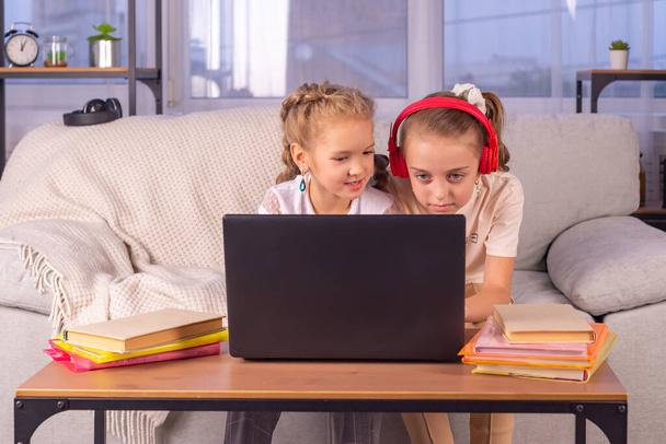 boldog család együtt. Két nővér nézi a laptop képernyőjét. otthon tanulási koncepció - Fotó, kép