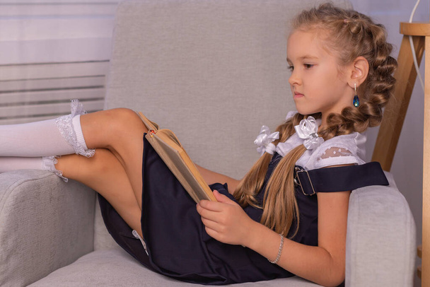 girl schoolgirl read a book at home. home schooling concept - 写真・画像
