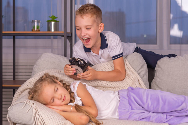 дівчинка і хлопчик школярі з будильником, який гучно дзвонить не хоче прокидатися вранці
 - Фото, зображення