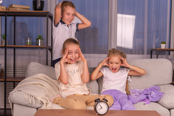 a girl and a boy schoolchildren with an alarm clock that calls loudly does not want to wake up in the morning - Foto, Bild